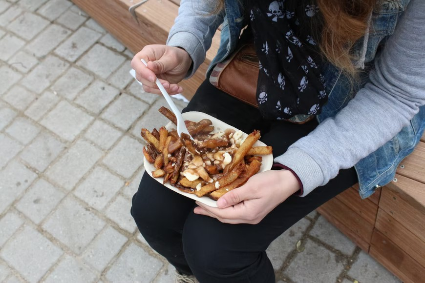A woman enjoying a delicious plate of poutine