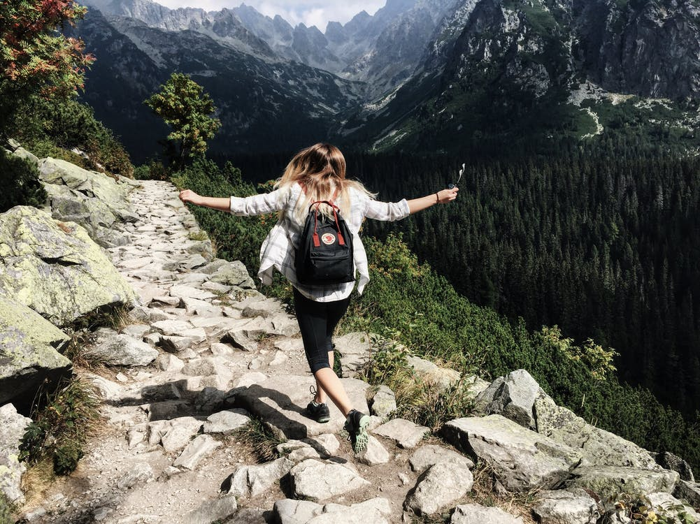 A woman wearing a backpack standing on a cliff during her hike