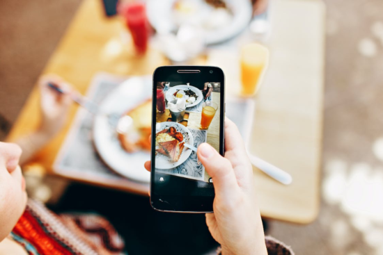 A food blogger taking a picture of served food