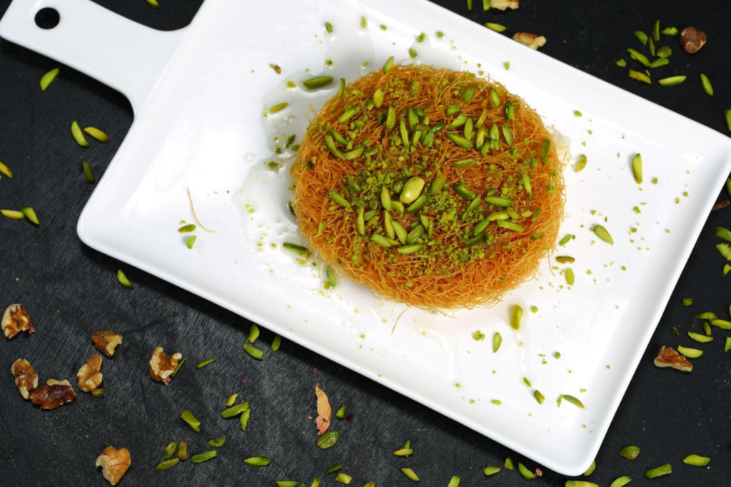 Knafeh on white serving dish topped with pistachio