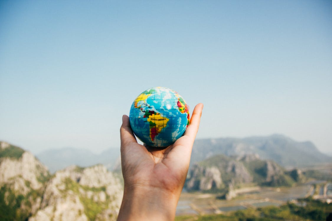 Holding a mini globe facing mountains