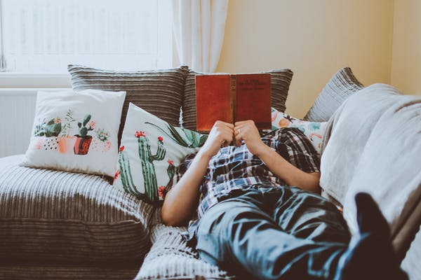 a person reading a book on the couch