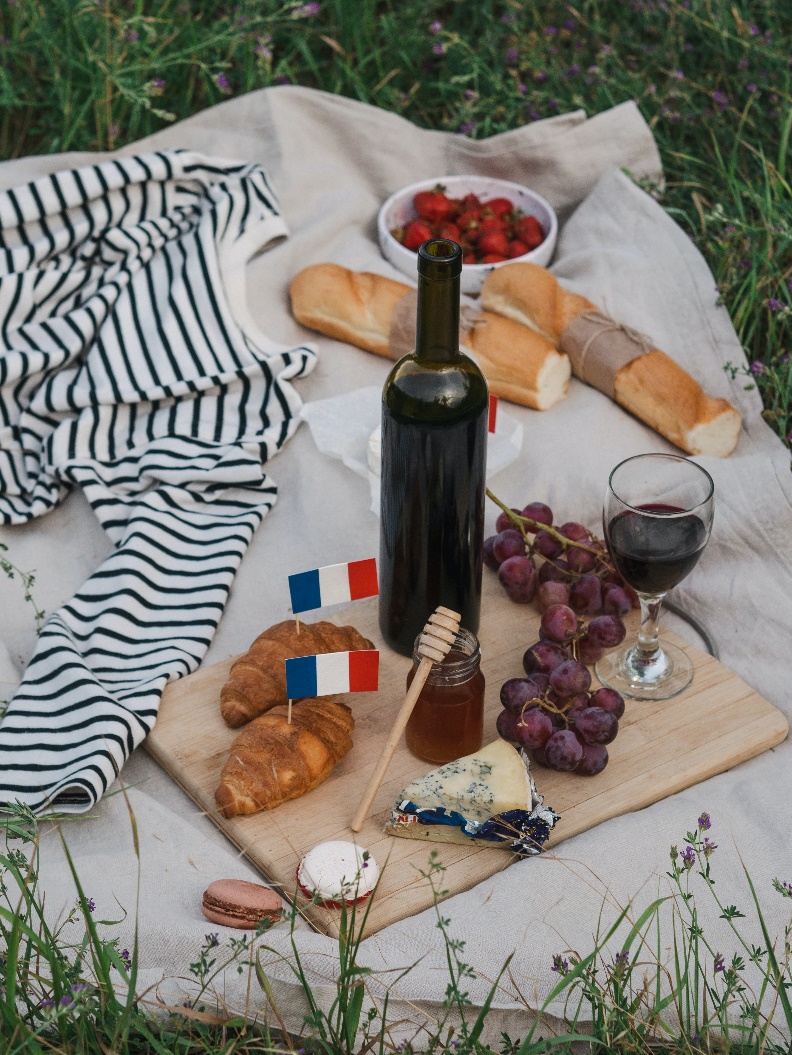 a wine bottle, cheese, and grapes on a board