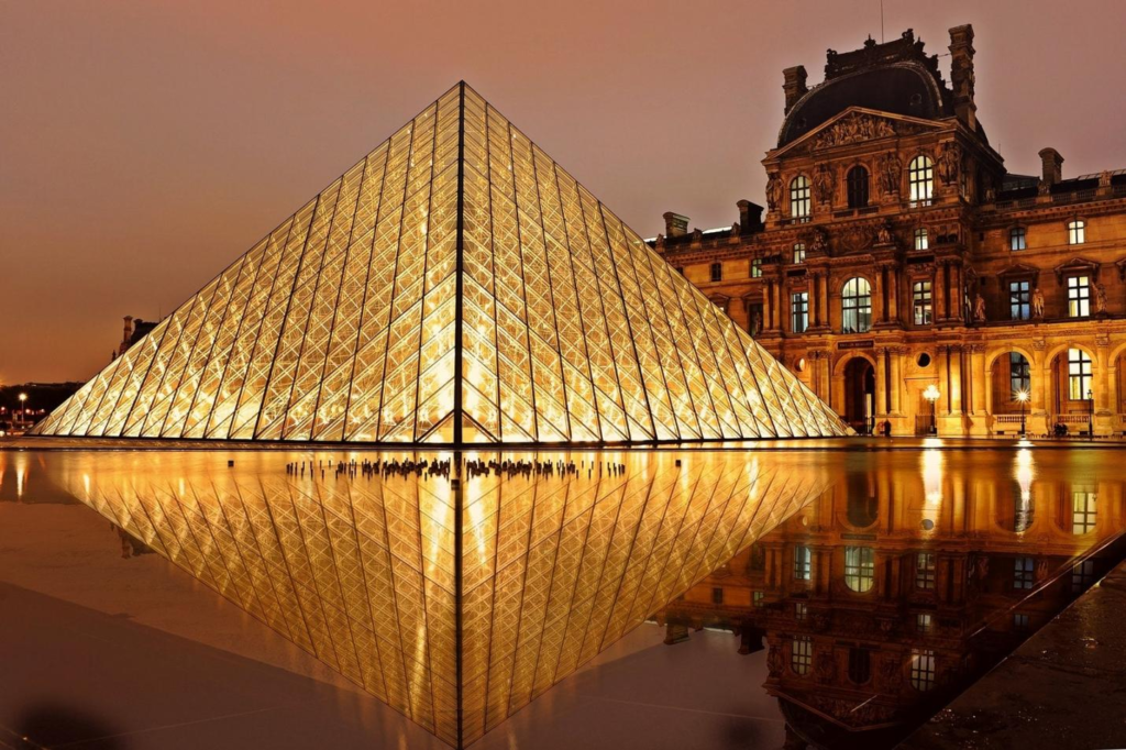 a nighttime shot of the exterior of the Louvre Museum in Paris, France