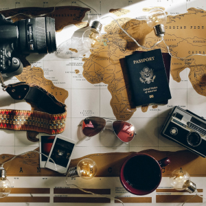 an image of a world map with cameras, passports, pictures, and other items lying on top Irina Bukatik