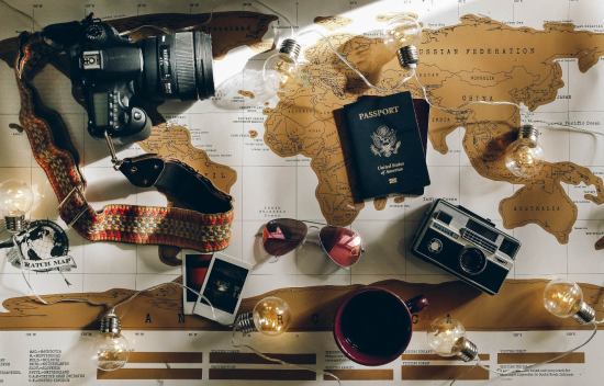 an image of a world map with cameras, passports, pictures, and other items lying on top